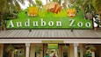The entrance to Audubon Zoo with a sign featuring a lion and a tiger.