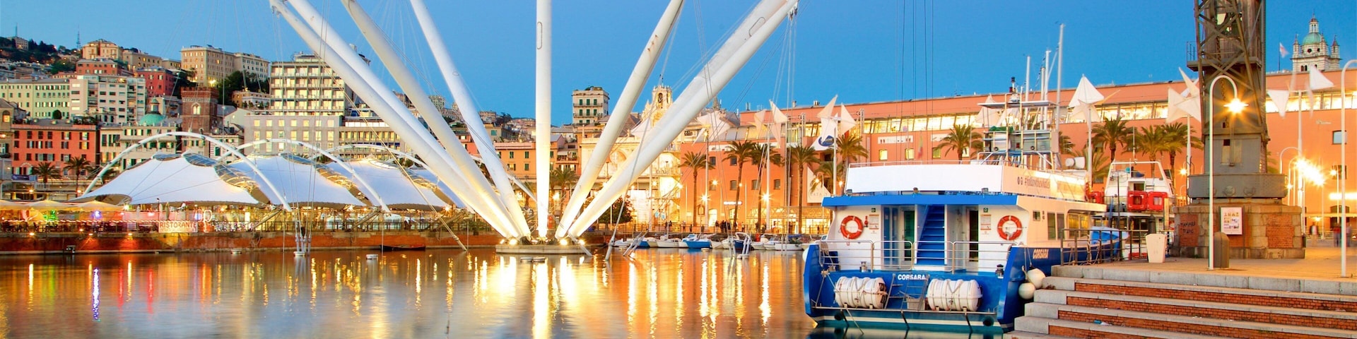 A waterfront with a modern bridge, boats, and a cityscape with buildings and a church.