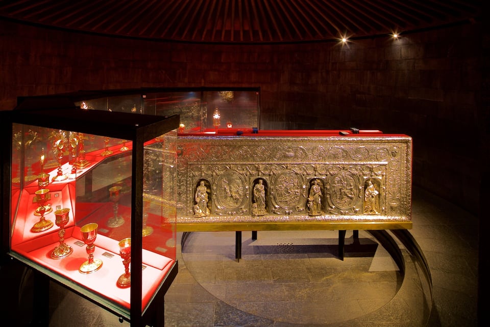 Une vitrine contenant des objets religieux et un sarcophage doré.
