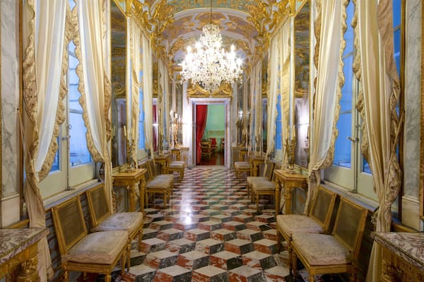 Un hall somptueux, orné de décorations dorées, avec un grand lustre et un sol à carreaux.