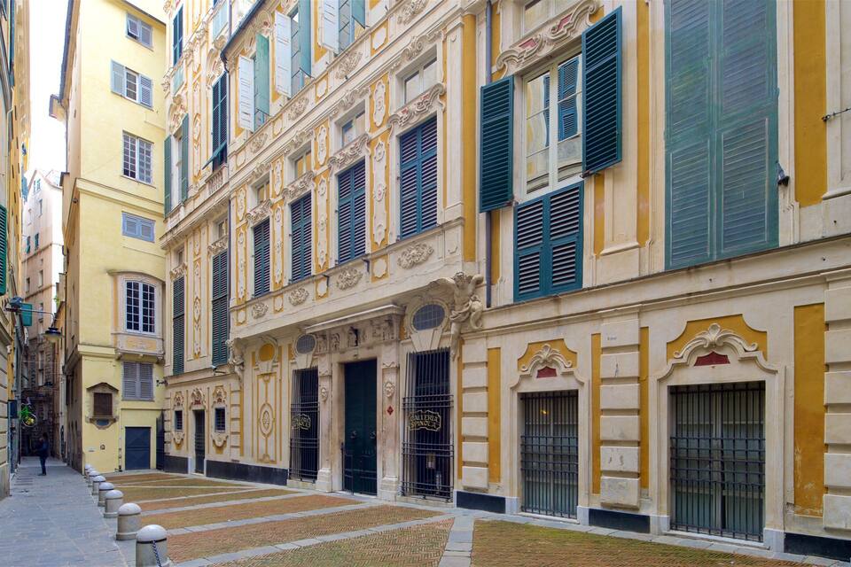 Rua estreita ladeada por edifícios históricos com fachadas ornamentadas e persianas verdes.