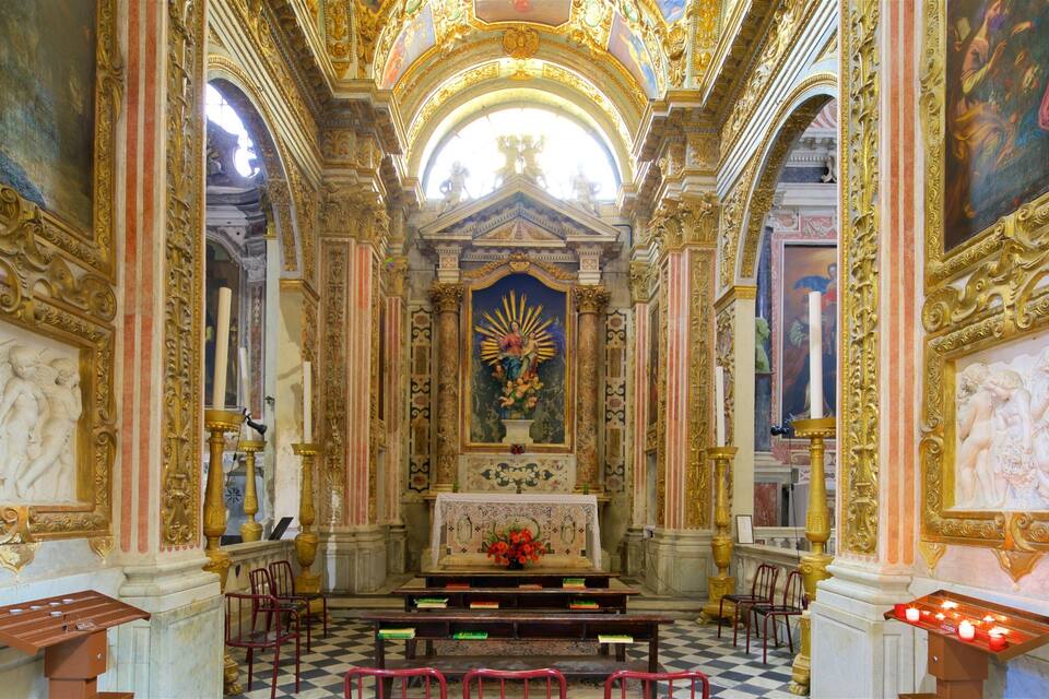 An ornate church interior with a central altar, red chairs, and a checkered floor.