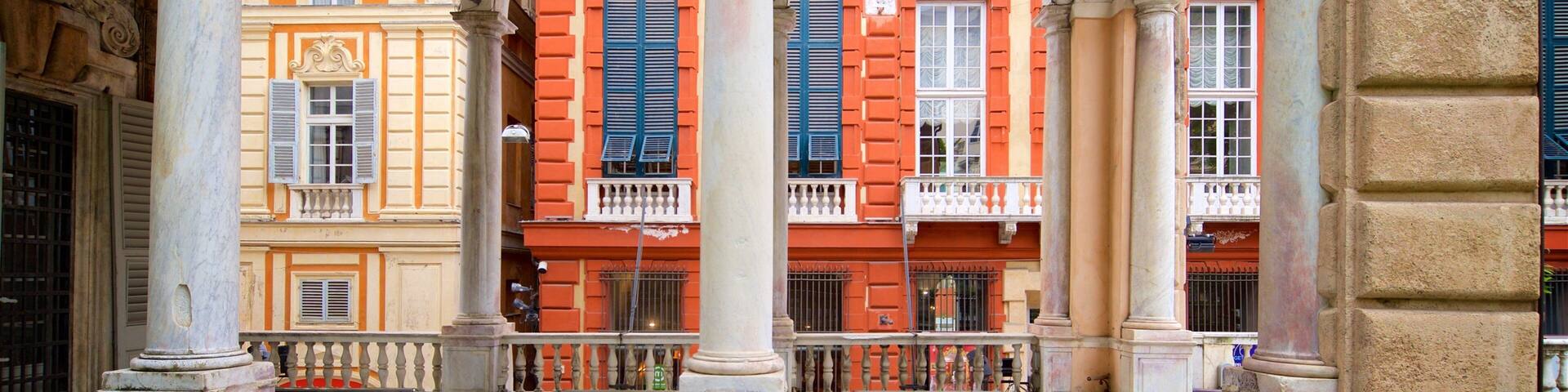 A covered pedestrian area with arches, columns, and buildings with red and yellow facades.