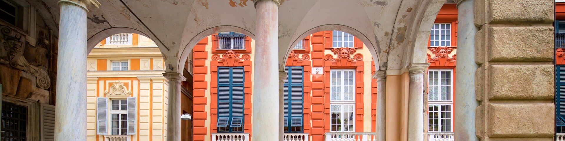 A covered pedestrian area with arches, columns, and buildings with red and yellow facades.
