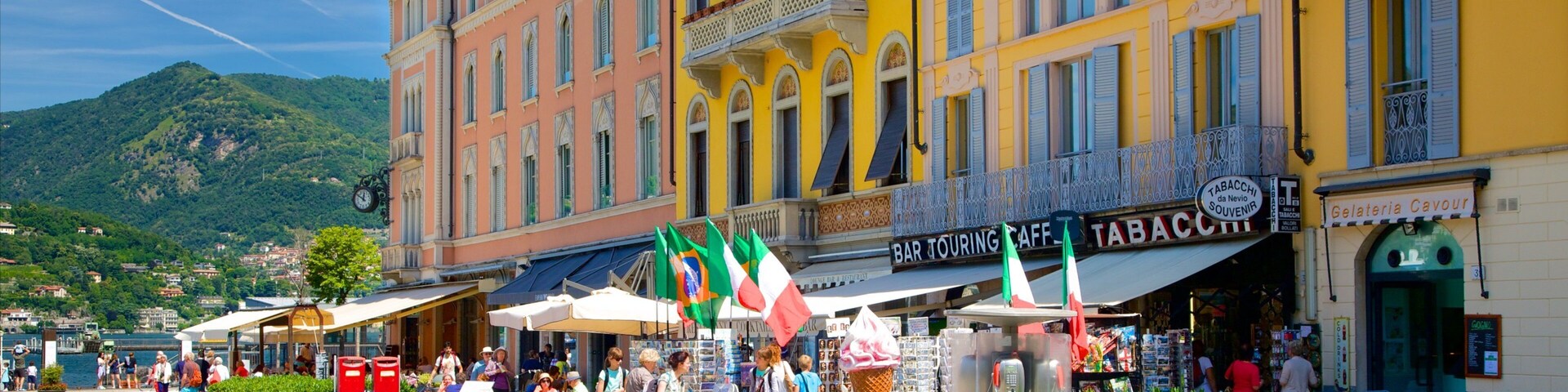 Una plaza animada con edificios coloridos, cafés al aire libre y una montaña de fondo.