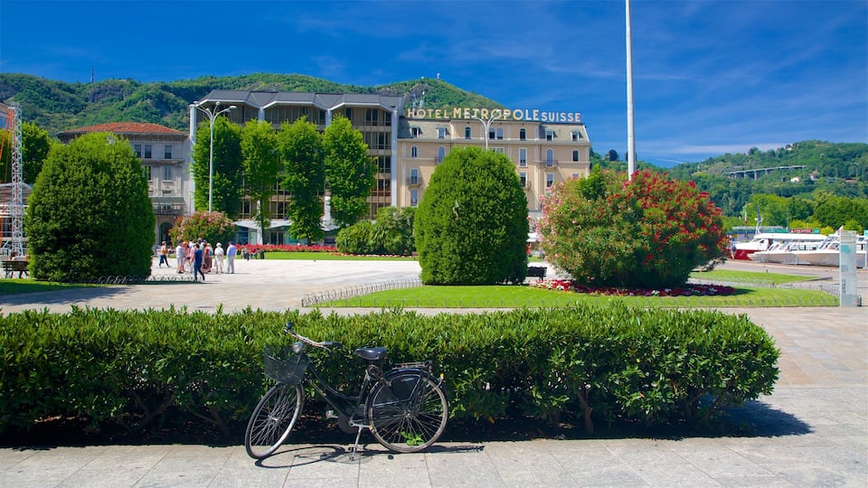 A hotel named "HOTEL METROPOLÉ SUISSE" with a mountainous backdrop, a bicycle, and a well-maintained garden.