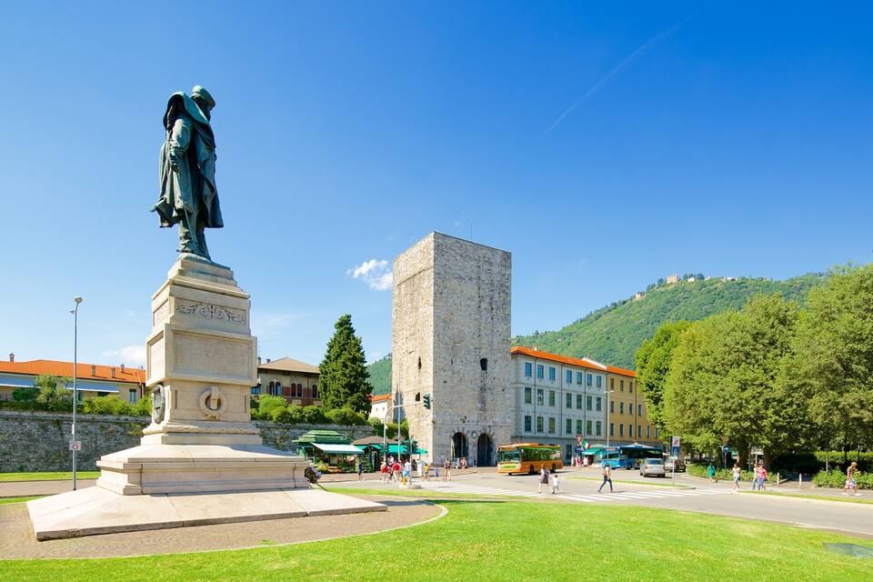 Una estatua, una alta torre de piedra y una colina verde al fondo.
