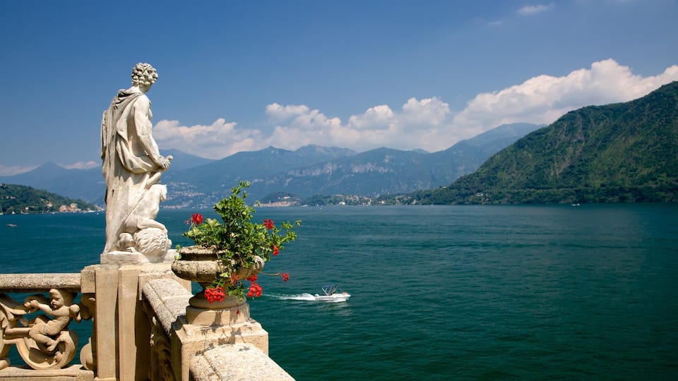 A statue overlooking a lake with mountains in the background.