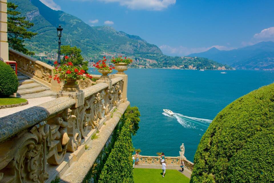 Una vista suggestiva di un lago con barche, una montagna sullo sfondo e architettura elaborata lungo la riva.