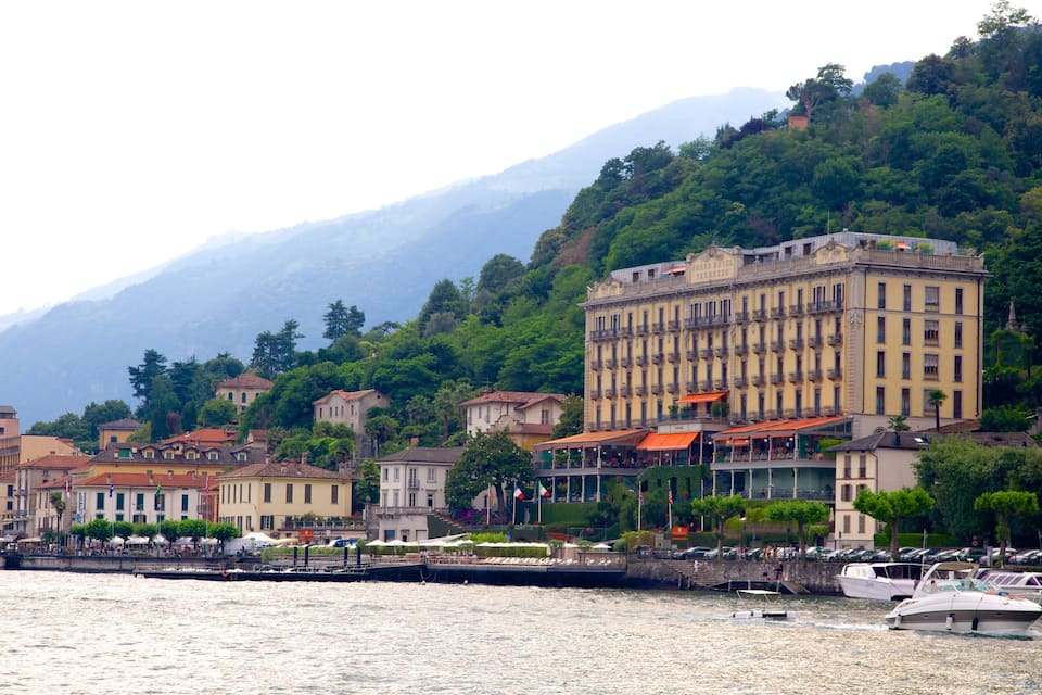 Una cittadina costiera con edifici storici, un porto turistico e montagne sullo sfondo.