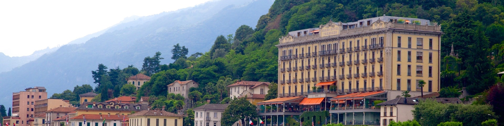 A coastal town with historic buildings, a marina, and mountains in the background.