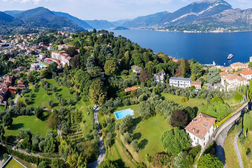 Eine Küstenstadt mit einem Yachthafen, üppiger Vegetation und Bergen im Hintergrund.