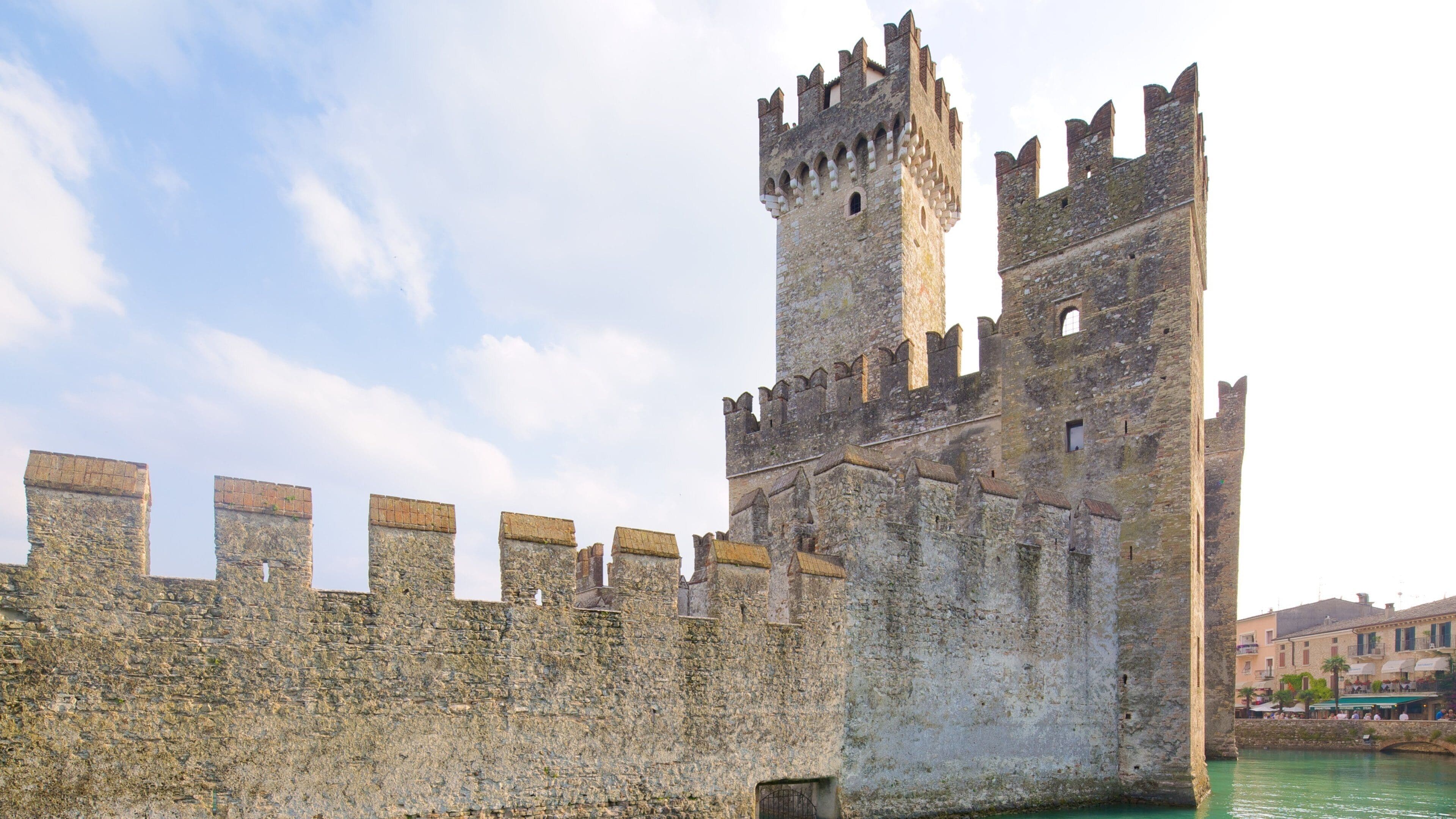Un castillo de piedra medieval con una torre alta y muros almenados.