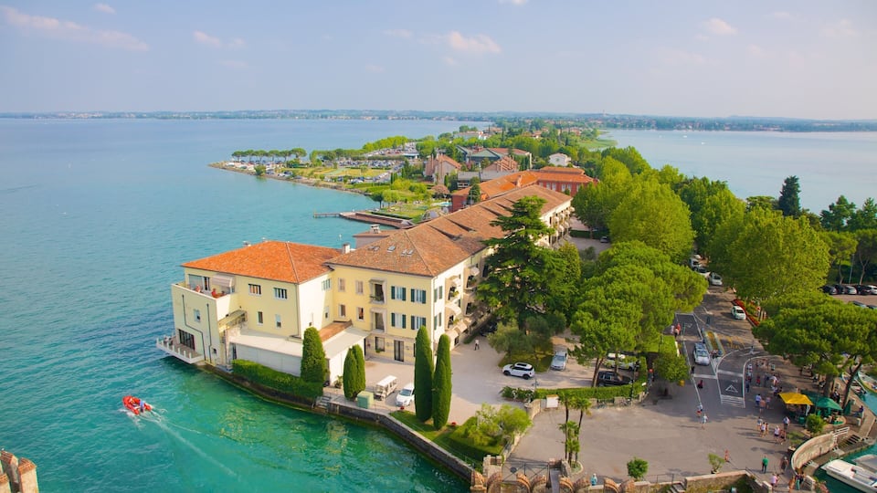 Un paese sul lago, con edifici lungo la riva, una barca e una passeggiata pedonale.
