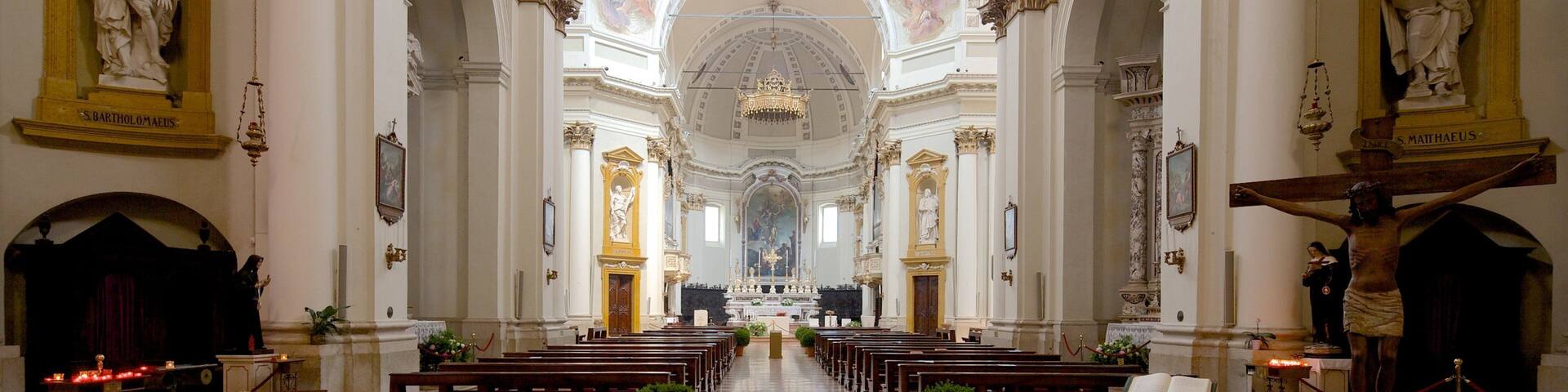A church interior with a high ceiling, ornate decorations, and a checkered floor.