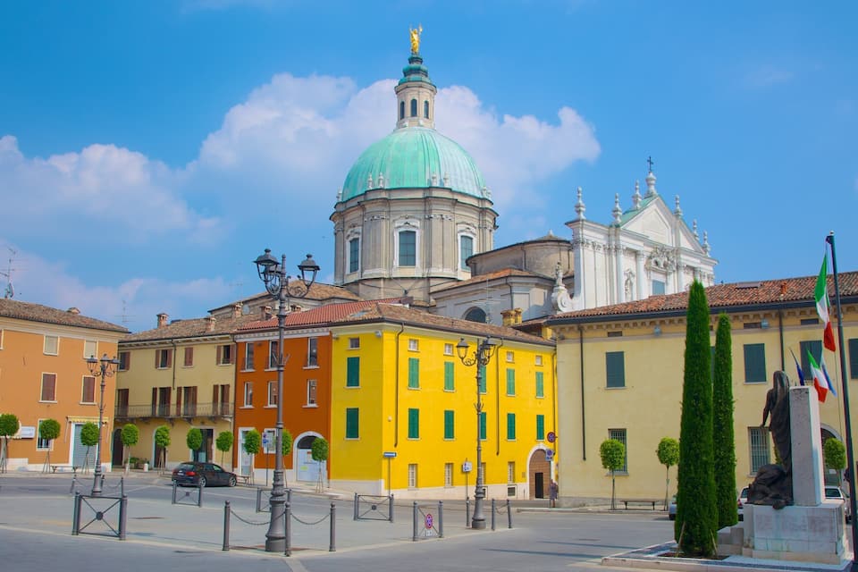 A street with colorful buildings, a prominent yellow building, and a large dome structure in the background.
