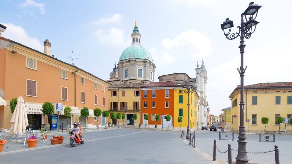 A street with colorful buildings, a prominent dome, and a statue on a pedestal.