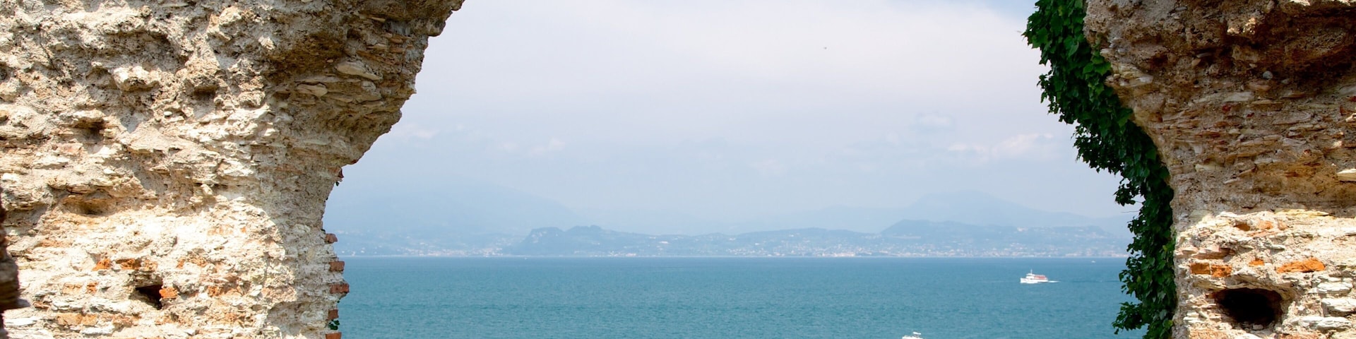 Grotte di Catullo caracterizando uma ruína, elementos de patrimônio e um lago ou charco