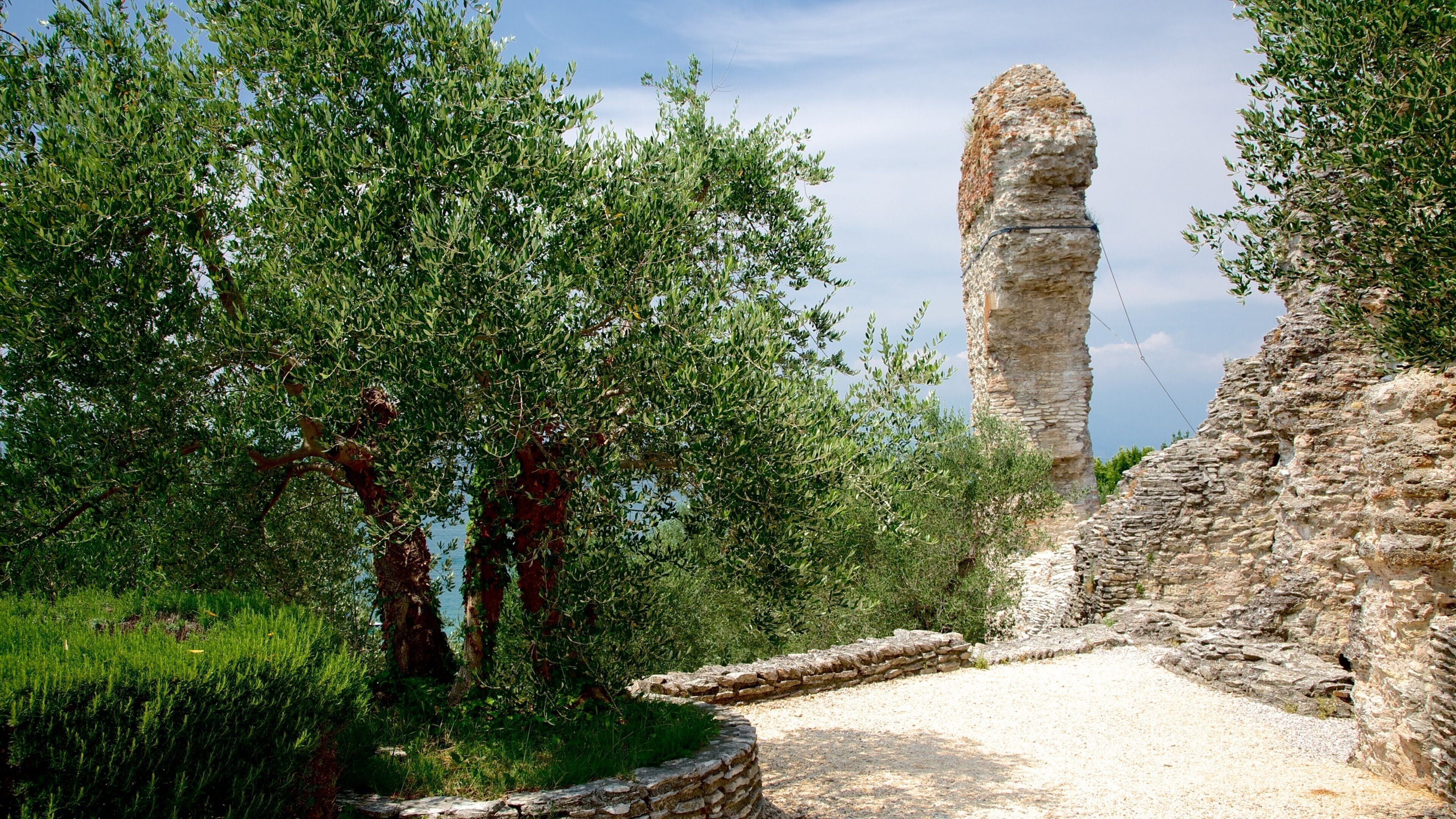 A stone pillar, a stone wall, and green trees.
