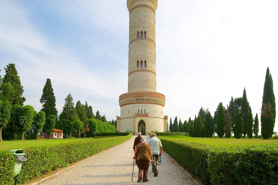 A tower with the inscription "A VITTORIO EMANUELLI III" surrounded by a well-maintained garden with hedges and tall trees.