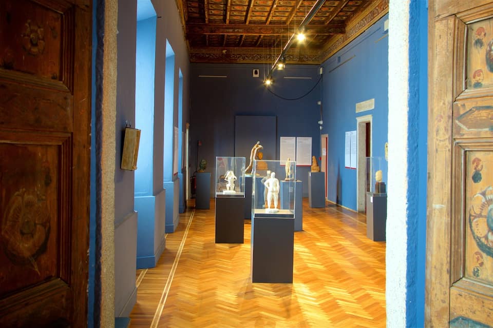 Ein Museumsflur mit Holzdielen, blauen Wänden und klassischer Deckenmalerei.