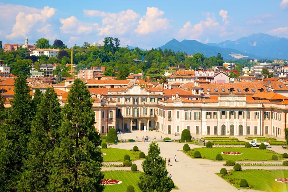 A historic building with a large courtyard surrounded by trees and manicured gardens.
