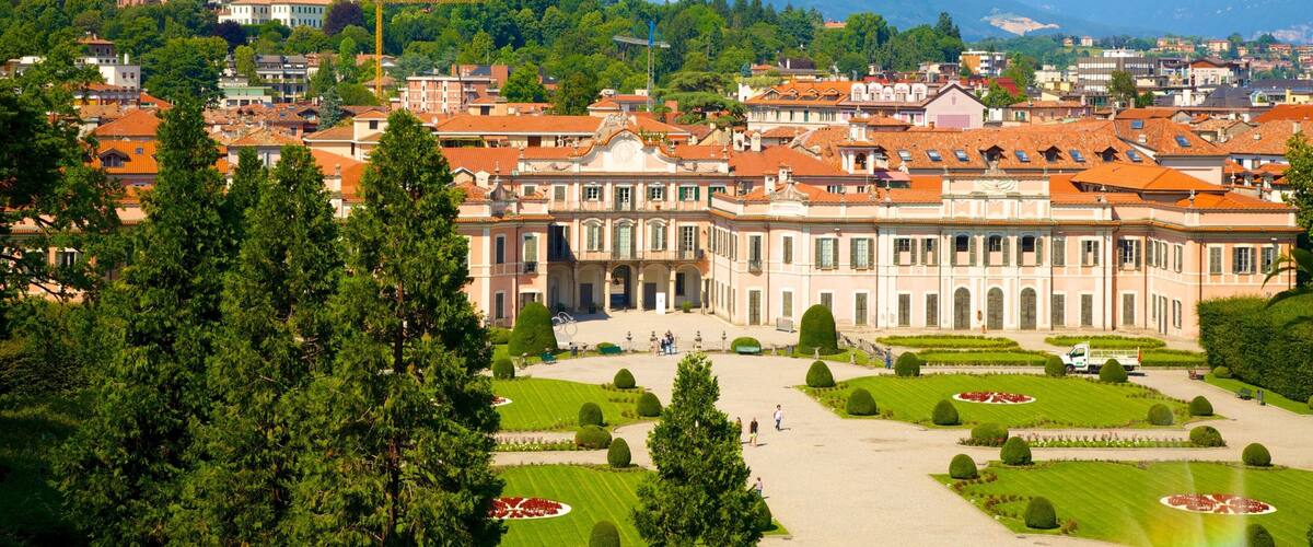 A historic building with a large courtyard surrounded by trees and manicured gardens.