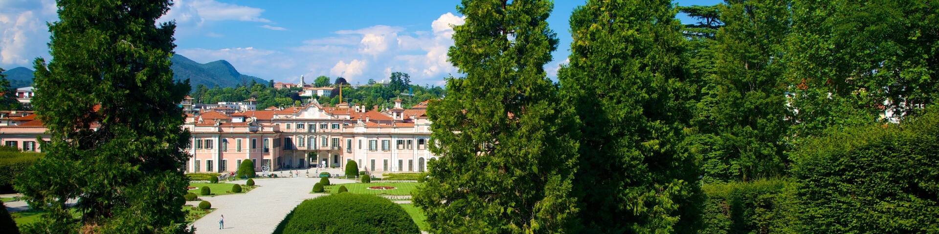 A grand palace with a formal garden, tall trees, and a clear blue sky.