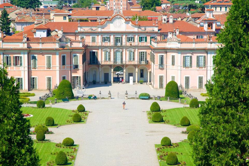 A grand building with a symmetrical facade, surrounded by well-manicured gardens and tall trees.