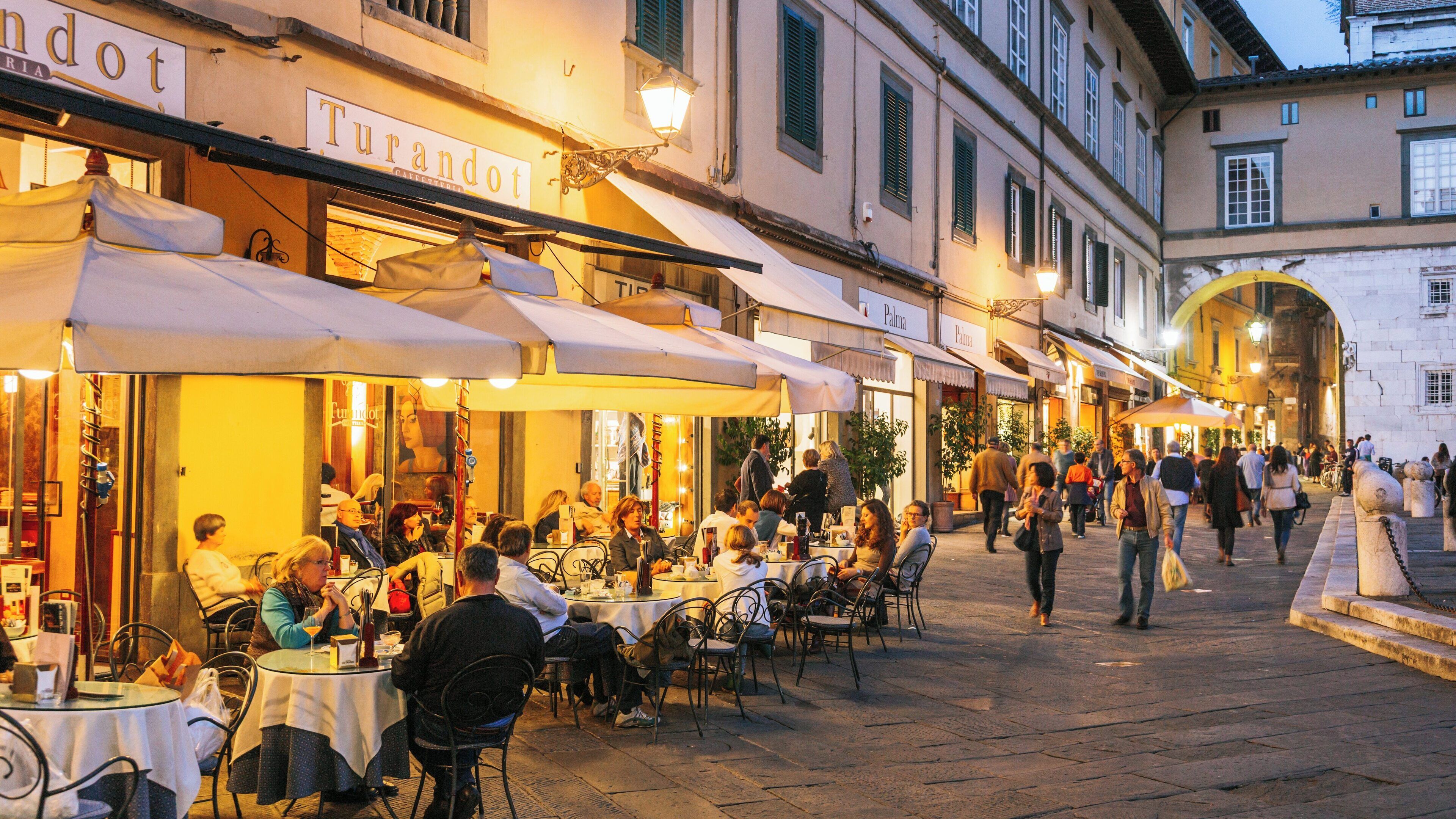 Dining under the charm of Piazza San Michele in Lucca, Tuscany during a lively evening gathering