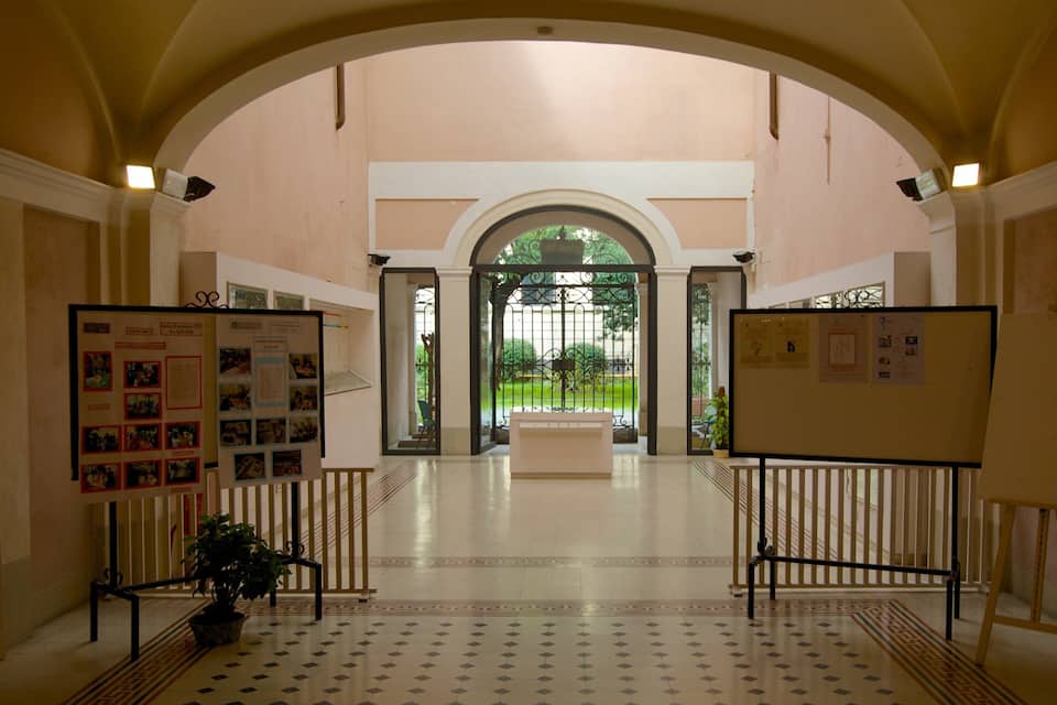 An indoor corridor with arched ceilings, tiled floors, and two display boards with informational posters.