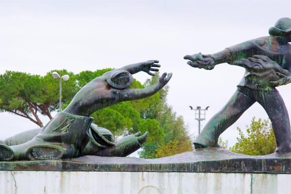 Une statue en bronze représentant deux personnages dans une pose dynamique, l’un tendant la main et l’autre pointant du doigt.