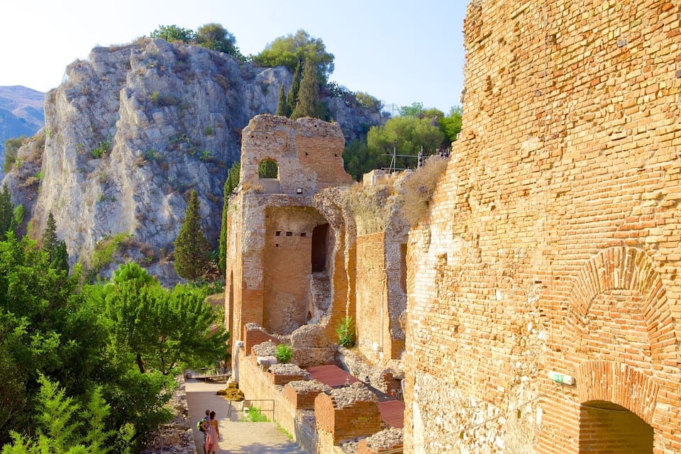 An ancient ruin with a large rock formation in the background.