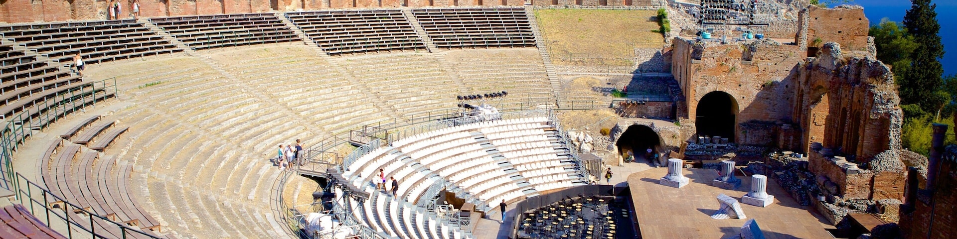 Um anfiteatro antigo com assentos em terraços e uma área de palco.
