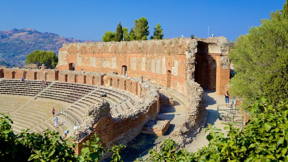 An ancient amphitheater with stone seating and a partially intact stage.