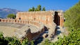 Un amfiteatre antic amb seients de pedra i un escenari parcialment conservat.