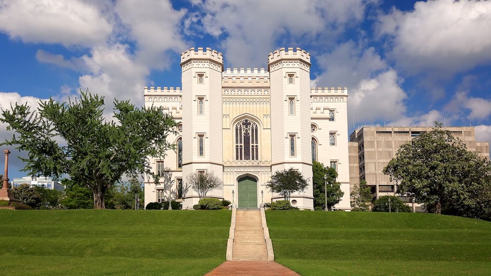 A castle-like building with a green door, surrounded by a well-maintained lawn and trees.