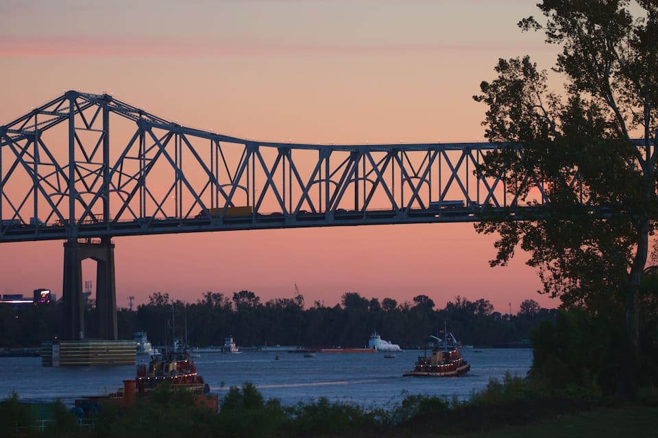 A bridge over a river at sunset with boats in the water.