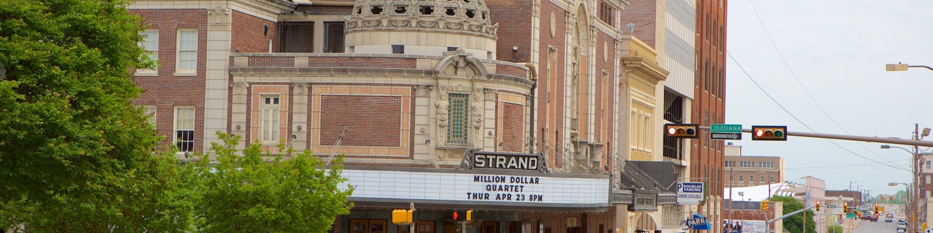 A street with a theater named Strand, cars, and a traffic light.