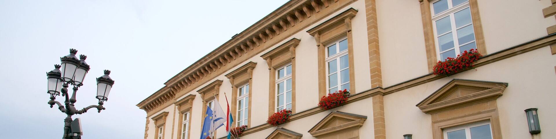A historic building with a statue of a lion, a flag, and flower boxes on the windows.