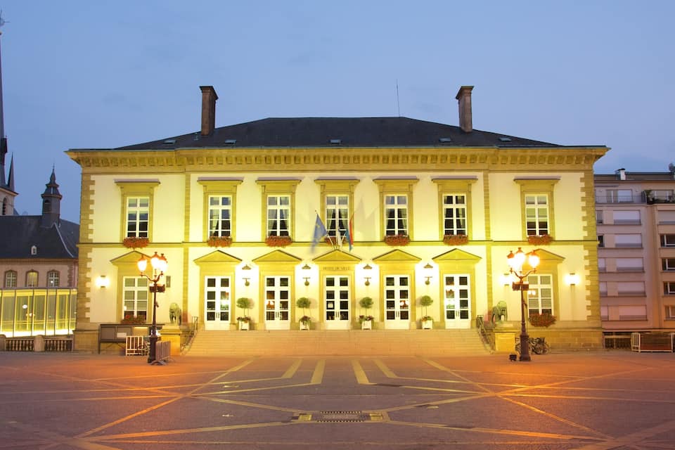 Een historisch gebouw met een brede gevel, meerdere ramen en een centrale ingang.