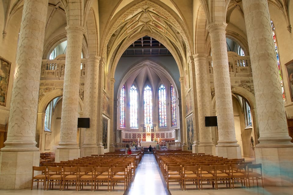 Een kathedraalinterieur met hoge gewelfde plafonds, grote glas-in-loodramen en rijen houten banken.