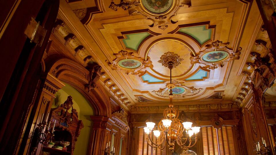 An ornate room with a chandelier, detailed ceiling, and wooden furniture.