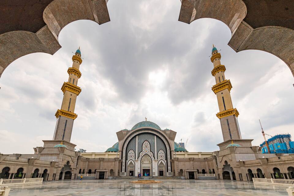 Een grote moskee met twee minaretten en een centrale koepel, omgeven door een ruime binnenplaats.