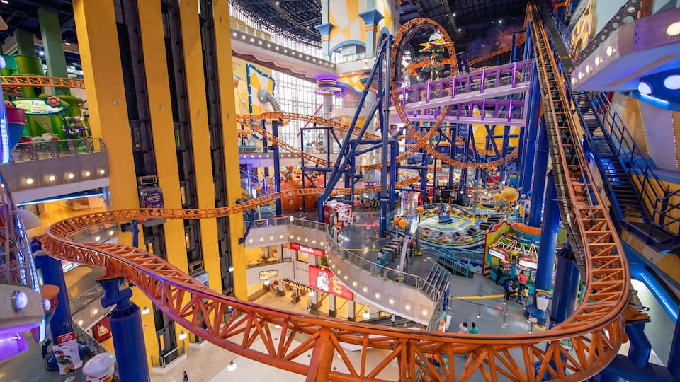 A multi-level indoor amusement park with roller coasters, a Ferris wheel, and various shops.