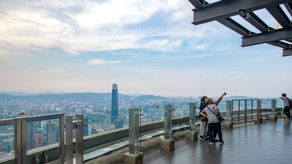A cityscape with a prominent skyscraper, a glass observation deck, and a railing.