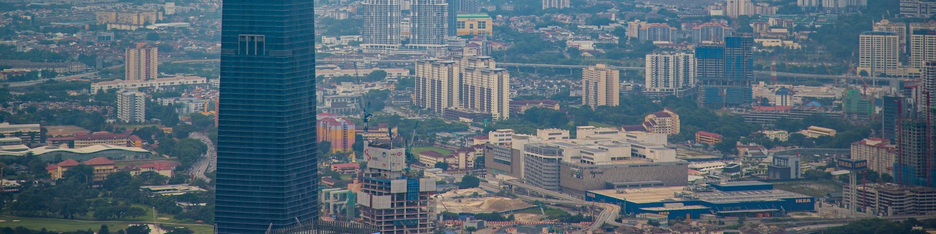 A cityscape with a prominent skyscraper, numerous residential and commercial buildings, and a hilly backdrop.