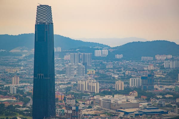 Un paysage urbain caractérisé par un gratte-ciel imposant, de nombreux immeubles résidentiels et commerciaux, et un arrière-plan vallonné.