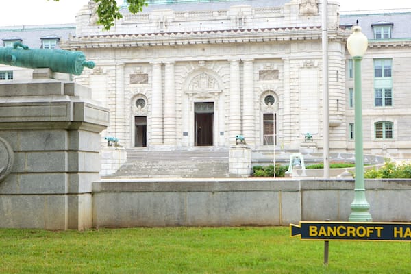 Un grand bâtiment à l’architecture riche et ornée, avec un canon et une enseigne indiquant « Bancroft Hall ».