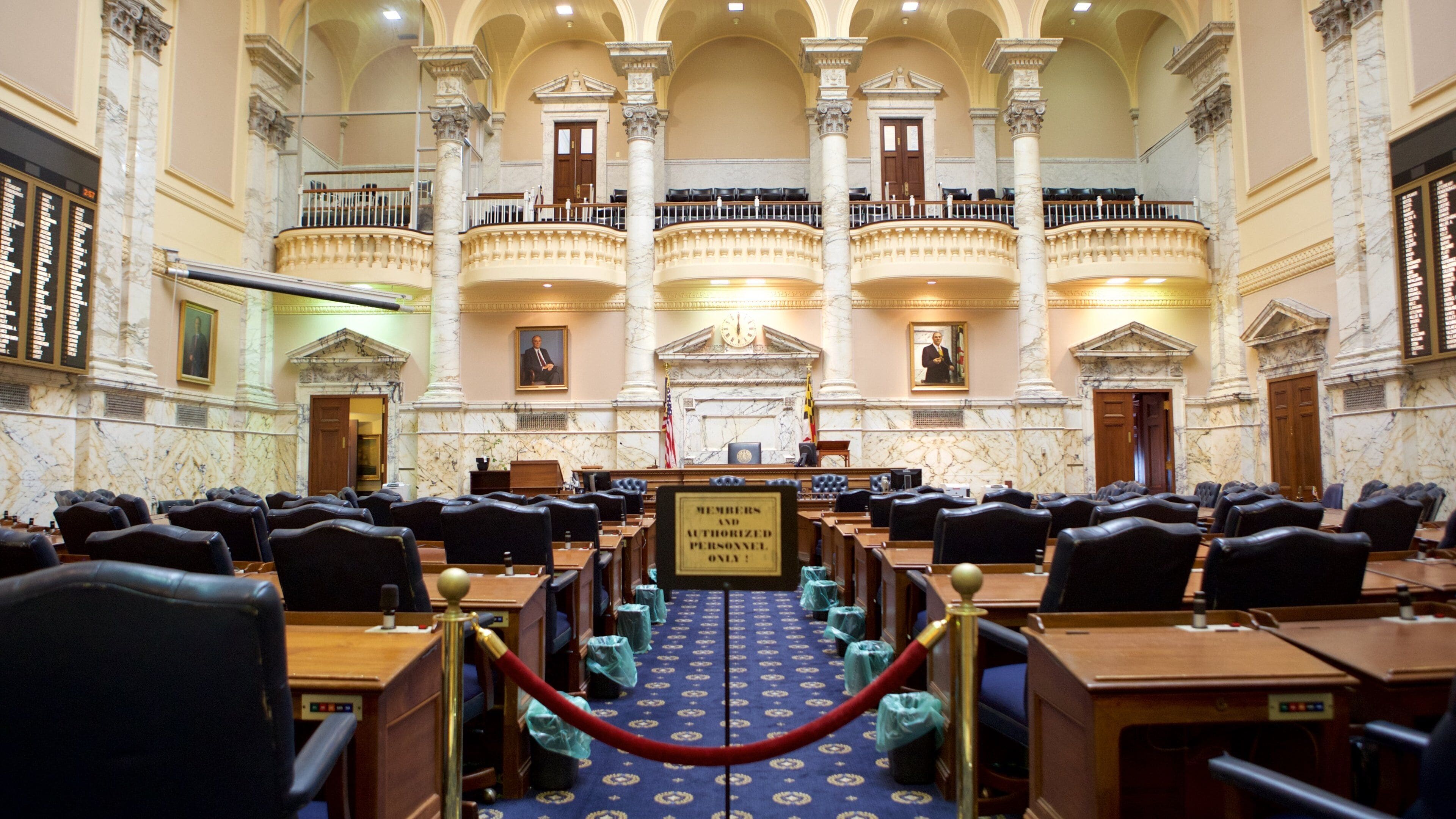A grand legislative chamber with marble columns, a central podium, and rows of seating.